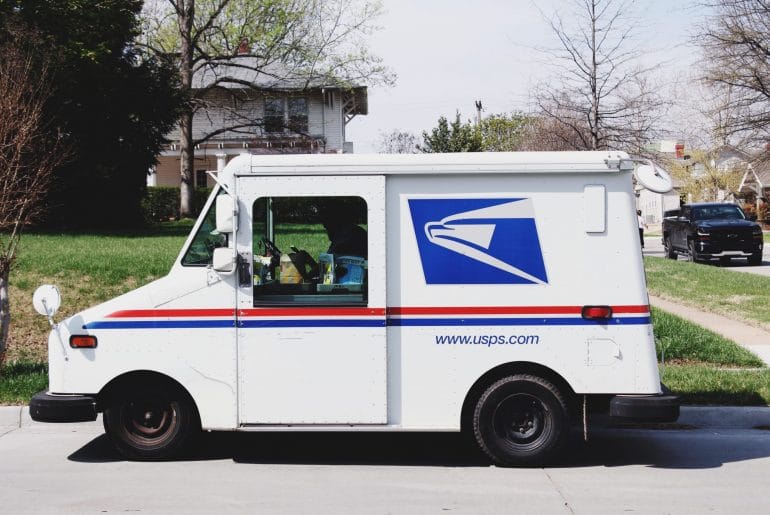 A United States Postal Service truck sitting outside on a suspiciously delightful day.