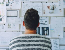 Student looking at a wall with papers of his financial plans