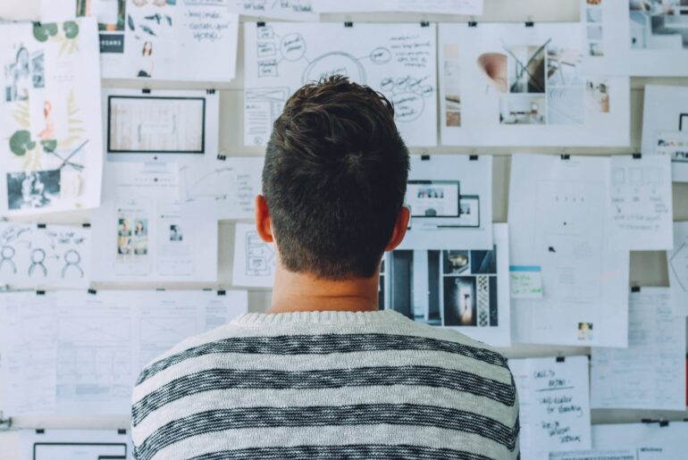 Student looking at a wall with papers of his financial plans