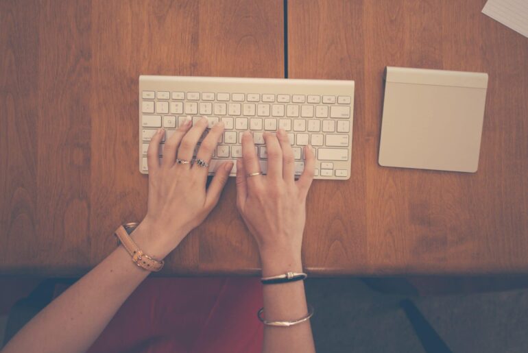 Woman typing her graduate school essay on a very small keyboard.