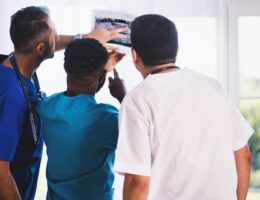 Three doctors examine an x-ray and seem to be very interested