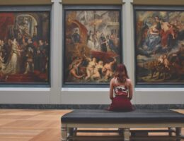 Woman sits in an art gallery looking at some really famous paintings