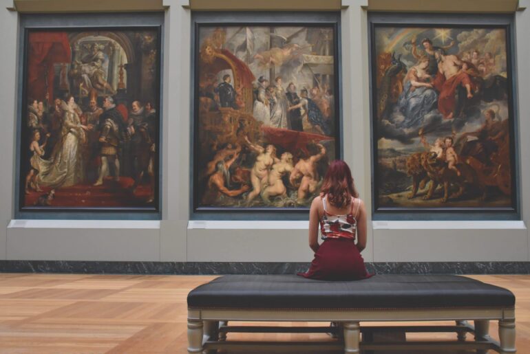 Woman sits in an art gallery looking at some really famous paintings