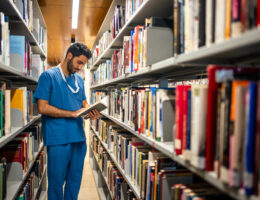 male student, choosing premed program who is in a library