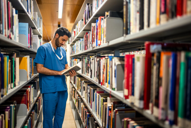 male student, choosing premed program who is in a library