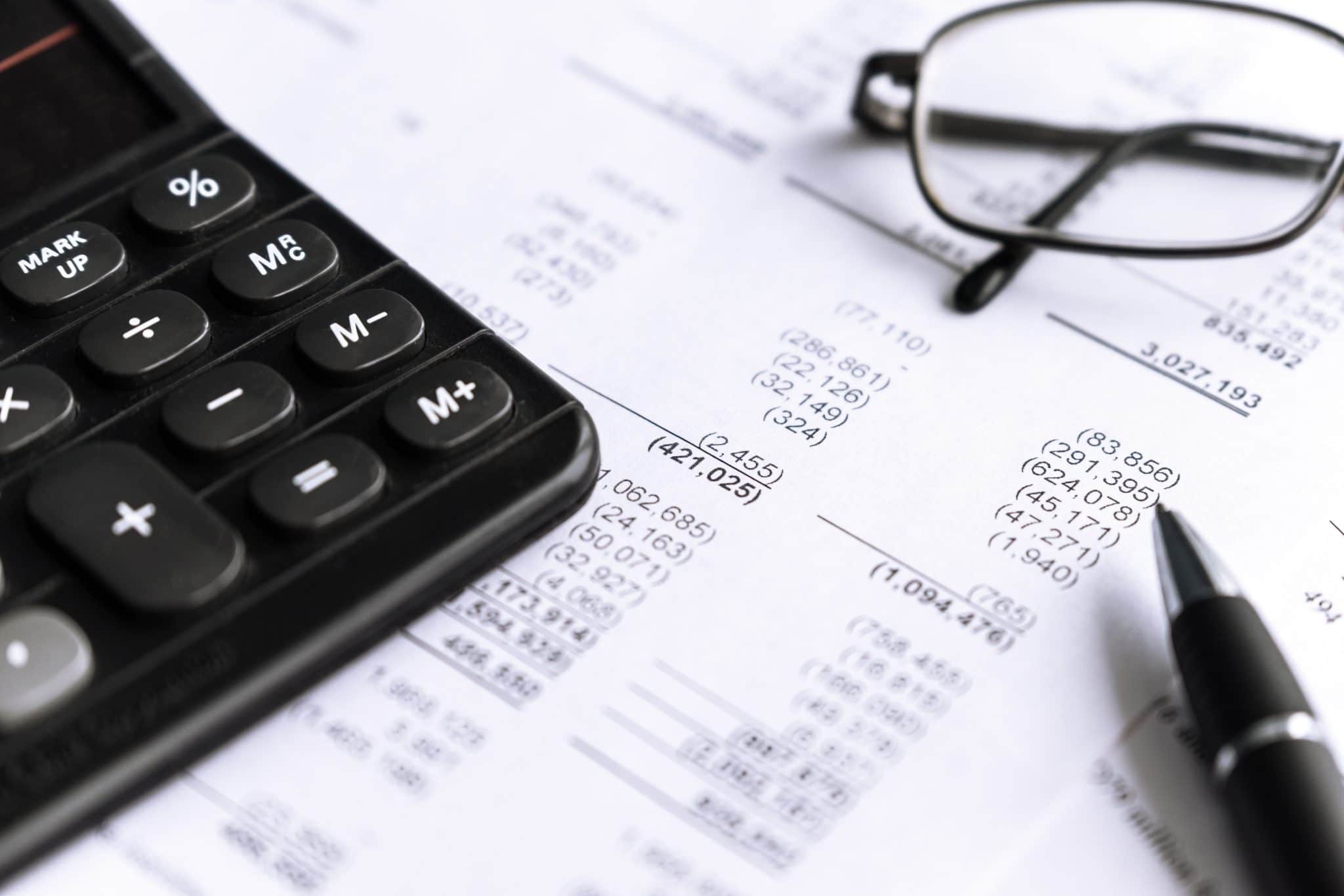 Investment and Financial analysis and reporting concept with Calculator, glass and pen. focus in center, selective.