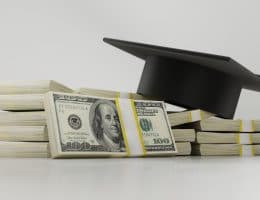 stack of money with graduation cap.