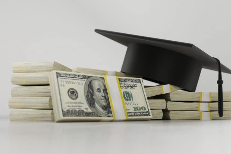 stack of money with graduation cap.
