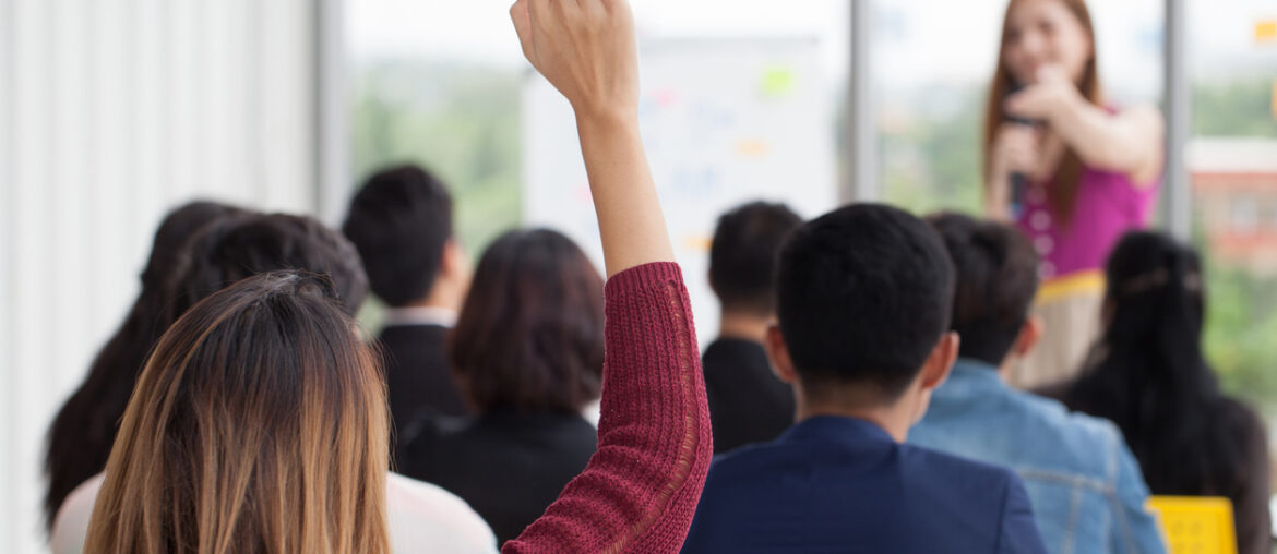 adult student raising hand in college classroom