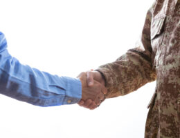 former military member shaking hands with civilian
