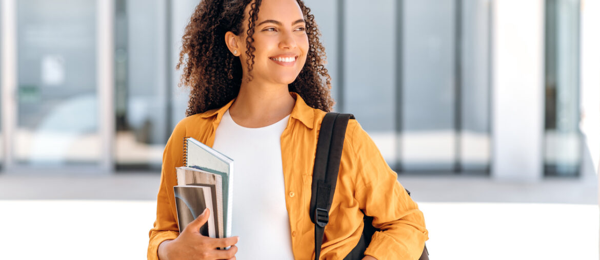 Student with backpack and books looking of into the distance with hope imagining her back-to-school success and being highly motivated.