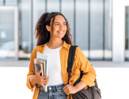 Student with backpack and books looking of into the distance with hope imagining her back-to-school success and being highly motivated.