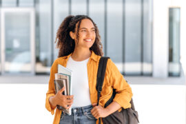 Student with backpack and books looking of into the distance with hope imagining her back-to-school success and being highly motivated.