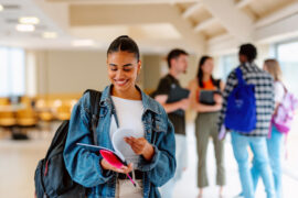 Student looking at their text books getting ready to craft an ACT study plan. Other students in the background chatting.