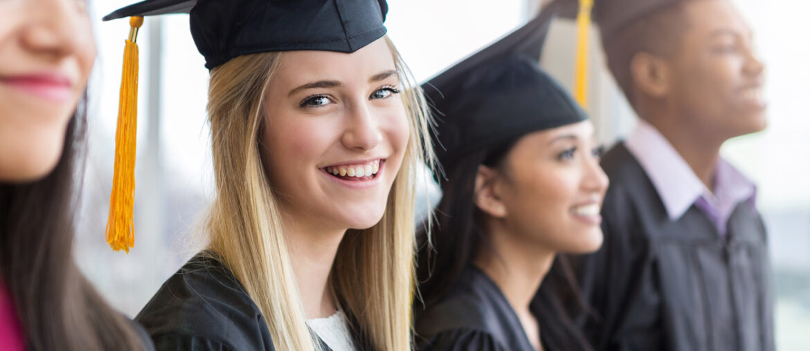 Teen girl at graduation considering her options after high school while she and her friends wait to be called on stage.