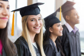 Teen girl at graduation considering her options after high school while she and her friends wait to be called on stage.