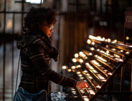 Girl lighting a candle after preparing for Catholic high school entrance exams, practicing faith while taking practice tests.