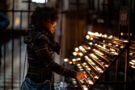 Girl lighting a candle after preparing for Catholic high school entrance exams, practicing faith while taking practice tests.