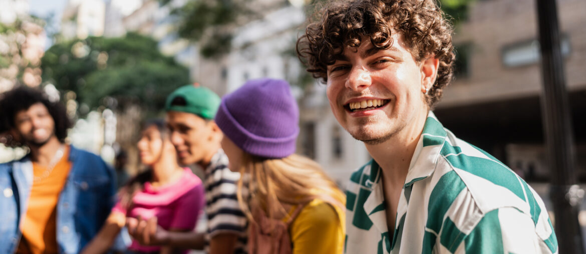 Smiling male-presenting student outdoors with friend group who believes that Failing a Credit-by-Exam Test Isn’t the End of the World.