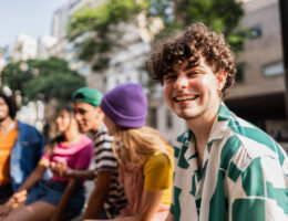 Smiling male-presenting student outdoors with friend group who believes that Failing a Credit-by-Exam Test Isn’t the End of the World.