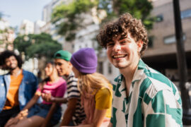 Smiling male-presenting student outdoors with friend group who believes that Failing a Credit-by-Exam Test Isn’t the End of the World.