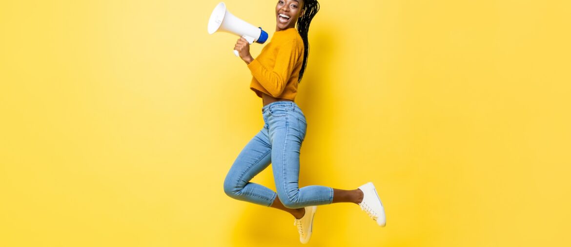 A female presenting student excited about being TOEFL test ready with a microphone