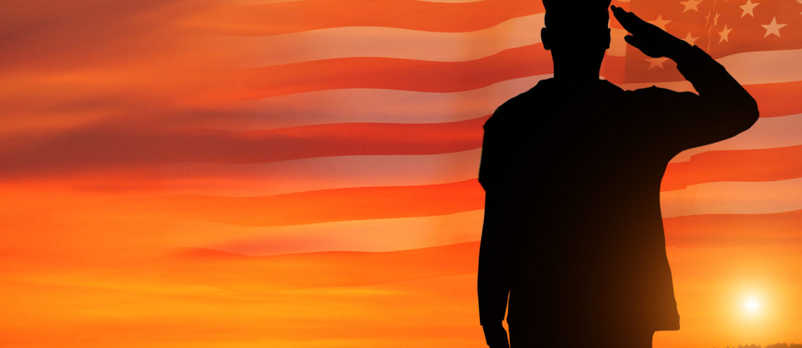Commissioned officer who took the OASC Test saluting in a sunset with a United States flag in the background