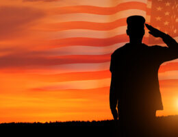 Commissioned officer who took the OASC Test saluting in a sunset with a United States flag in the background