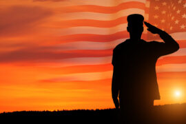 Commissioned officer who took the OASC Test saluting in a sunset with a United States flag in the background