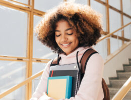 High Schooler carrying books and smiling because they have a defined ACT study plan