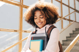 High Schooler carrying books and smiling because they have a defined ACT study plan
