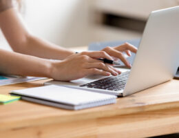 A student studies for their CLEP practice test on their laptop with notepad