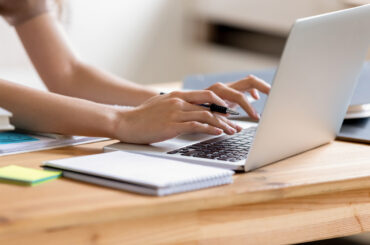 A student studies for their CLEP practice test on their laptop with notepad