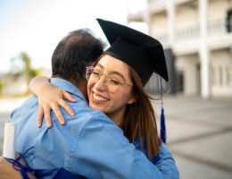 Student Hugging their Father in Cap and Gown After Graduating early using CLEP and DSST exams