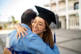 Student Hugging their Father in Cap and Gown After Graduating early using CLEP and DSST exams