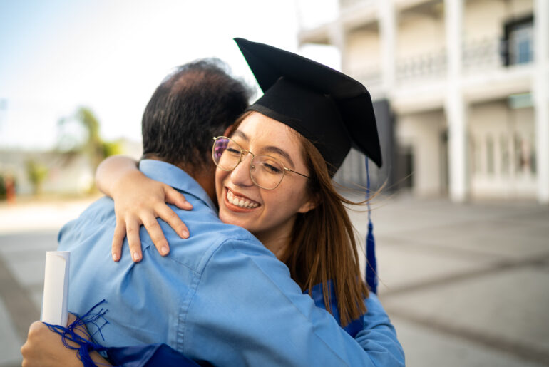 Student Hugging their Father in Cap and Gown After Graduating early using CLEP and DSST exams