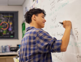 Male student solving algebra equations