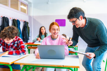 Teacher helping a student with a computer assignment